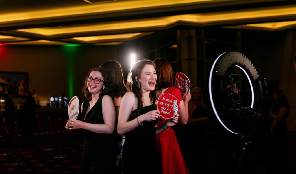 Ladies enjoying having their photos taken at a party by the 360 booth, holding signboards