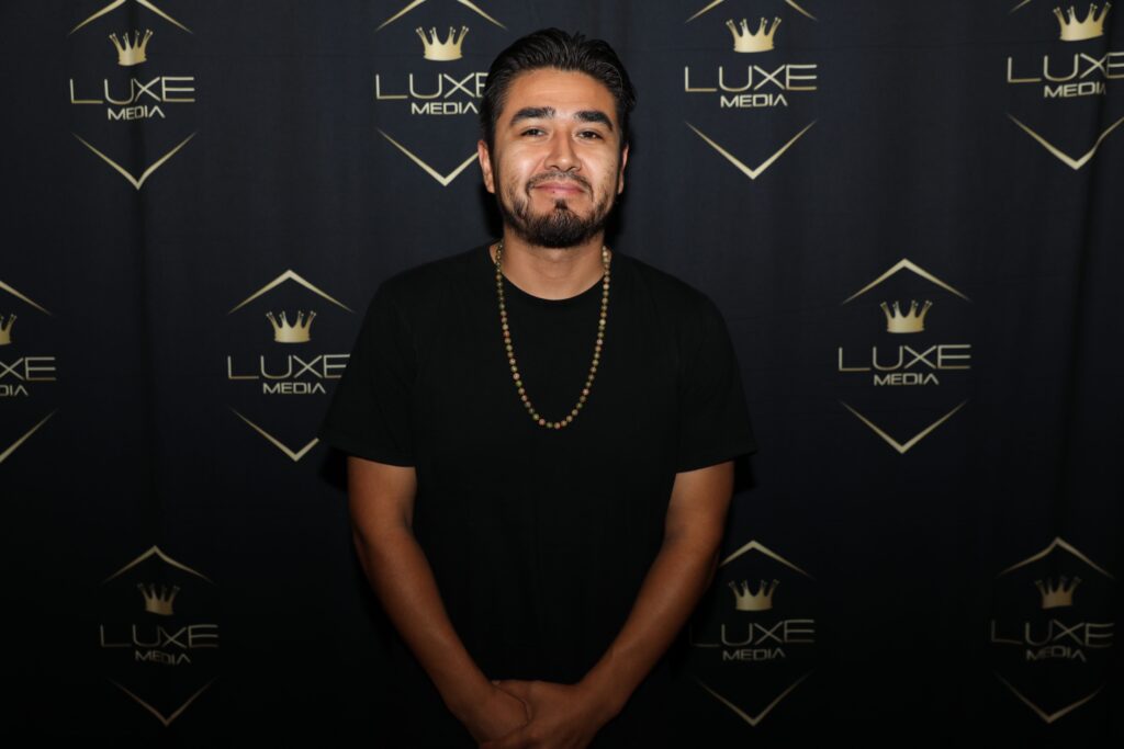 employee posing in front of gold and black custom backdrop