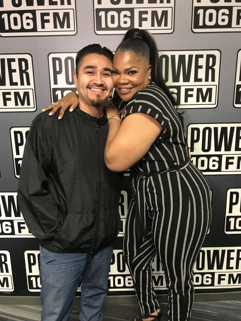 colleagues hugging in front of a corporate branded backdrop