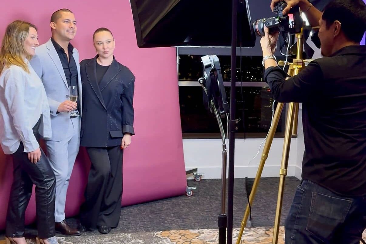 group of people taking a photo with photo booth in front of pink backdrop