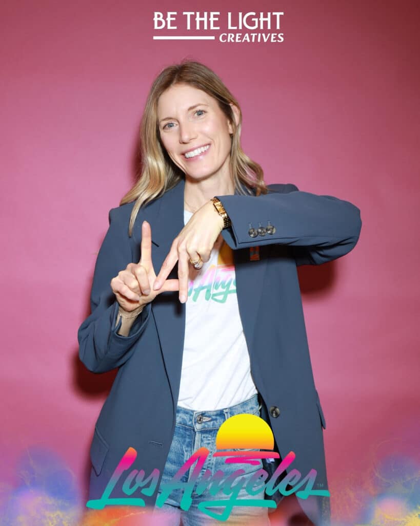 Woman smiling and posing at LA Tourism event activation with branded backdrop and photo studio experience.