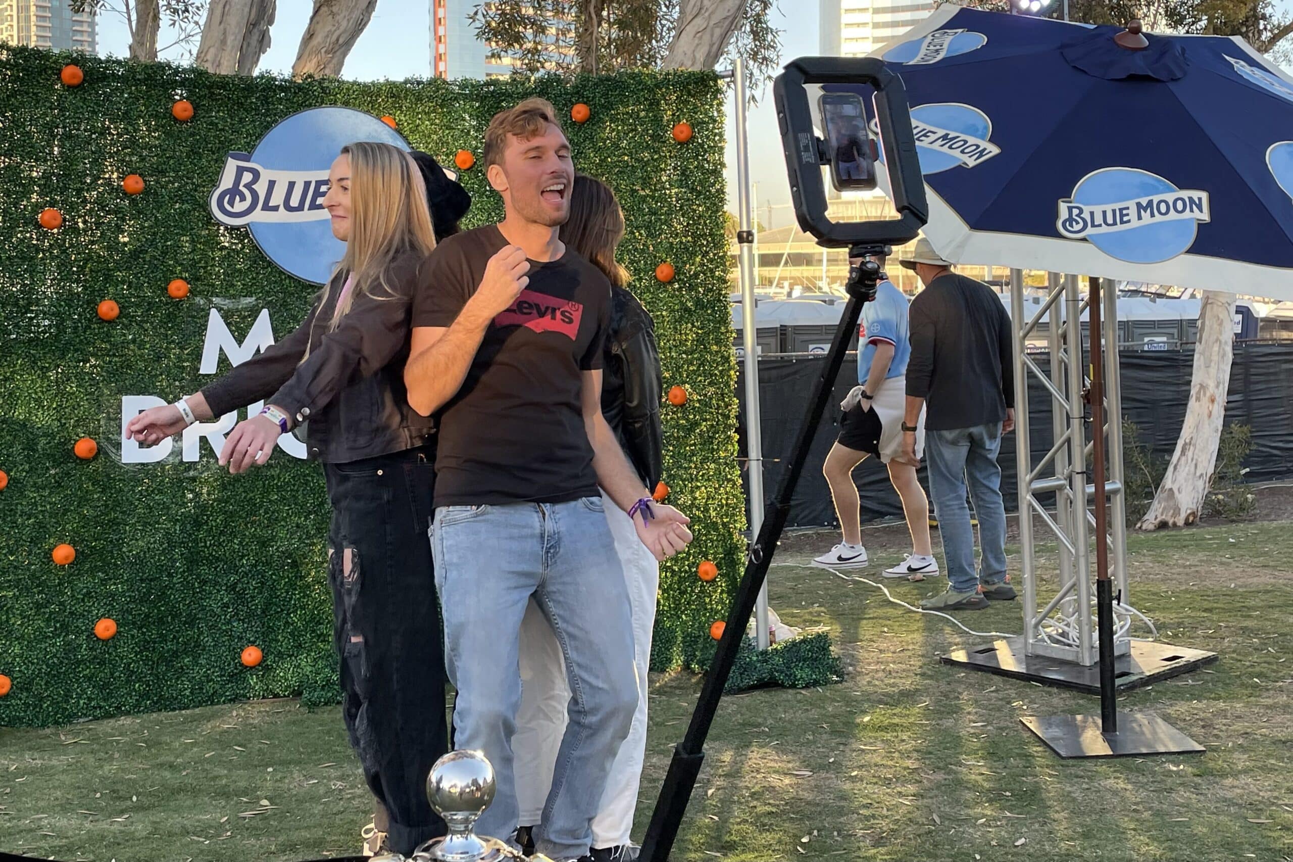 People standing on a 360 video booth platform taking a video in front of custom backdrop