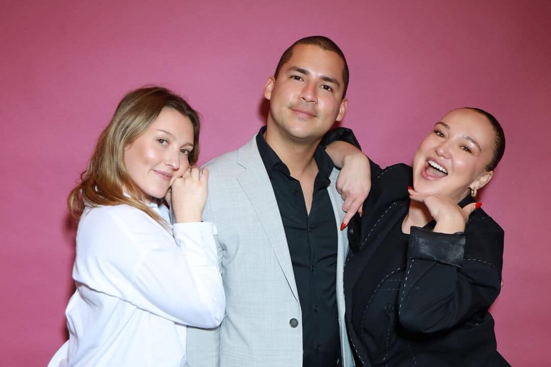 A group of three people taking their photo in front of a photo booth