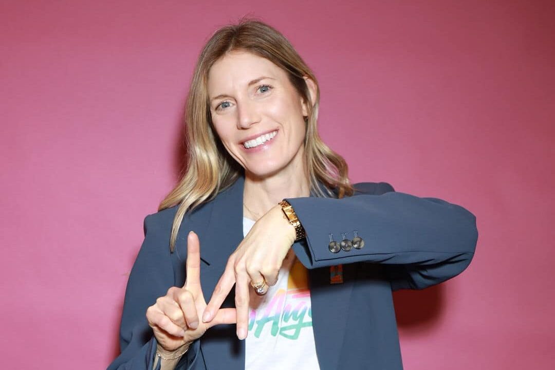 A woman posing in front of a pink backdrop